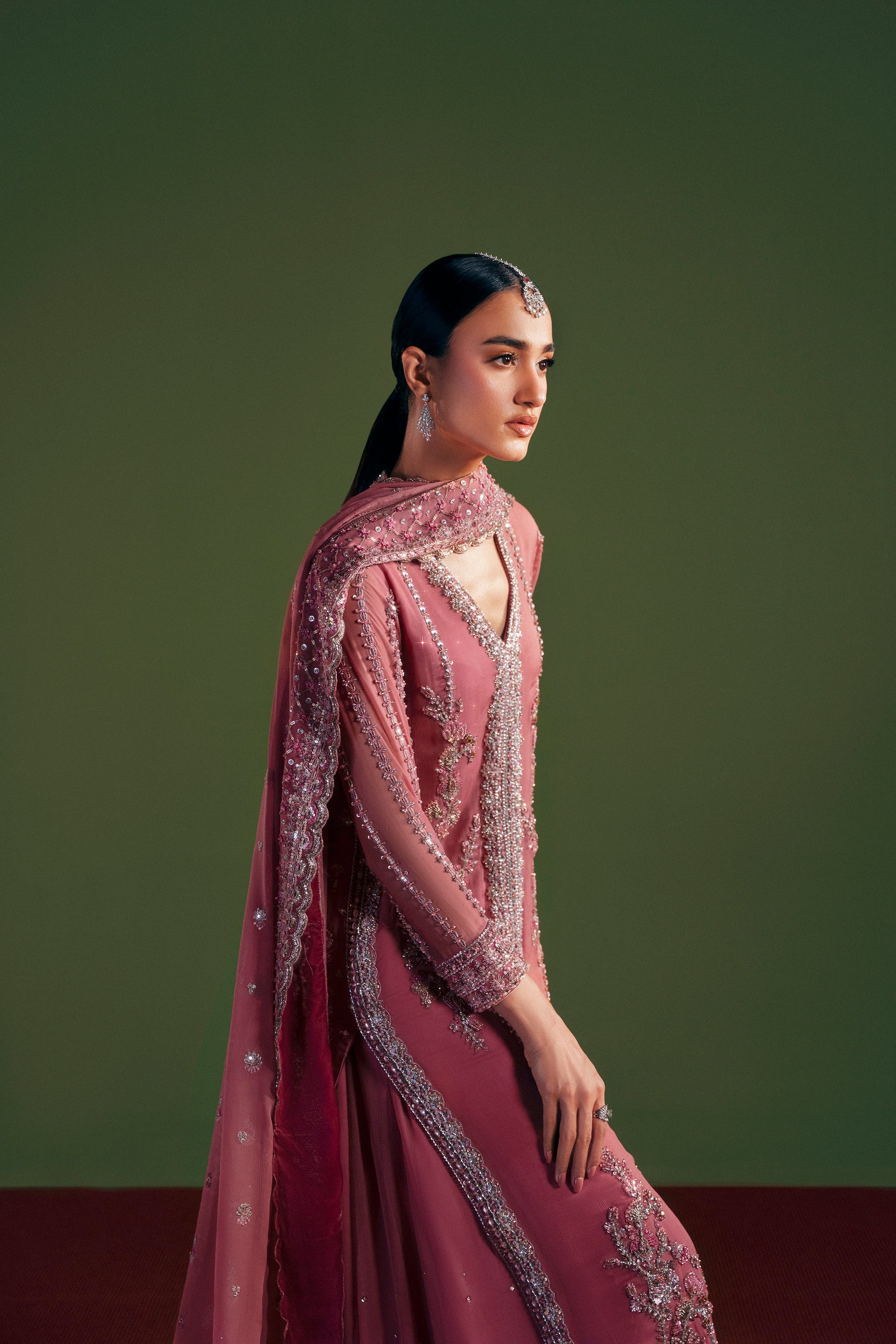 Woman in a pink embroidered traditional outfit against a green background|designer women’s clothing embroidered long shirt detail