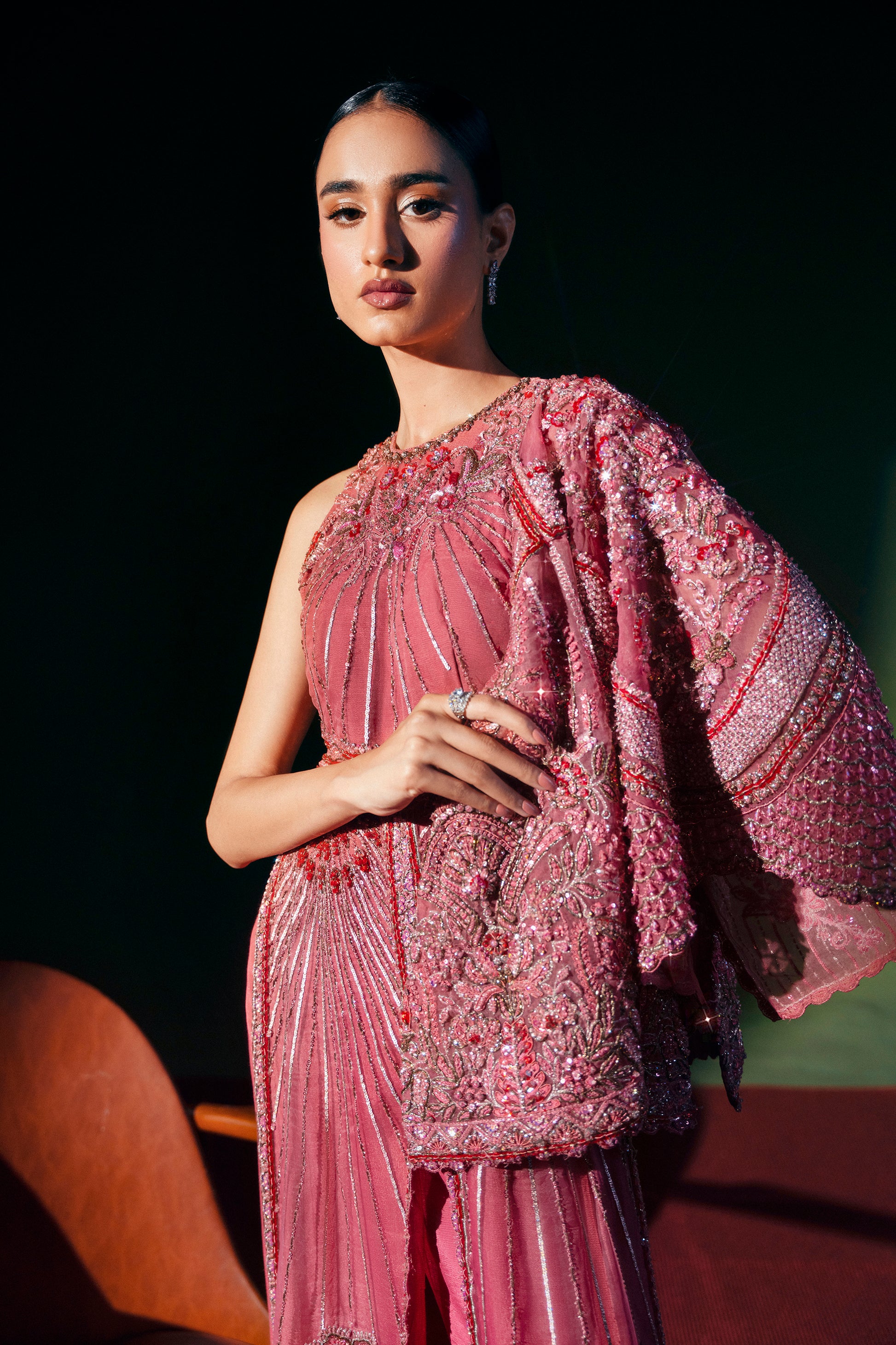 Woman in a pink embroidered outfit holding a glass against a dark background|formal women’s clothing 3-piece ensemble bridal event wear
